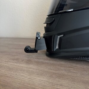 May include: A black motorcycle helmet with a clear visor and a black camera mount attached to the side.