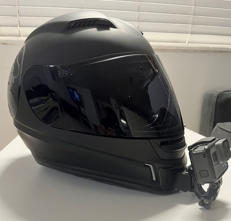 May include: A black motorcycle helmet with a clear visor and a GoPro camera mounted on the side.