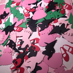 Peut inclure: Une collection de confettis en papier de différentes formes et couleurs, notamment rose, vert, noir et rouge. Les formes comprennent une sorcière, une robe et une paire de chaussures.