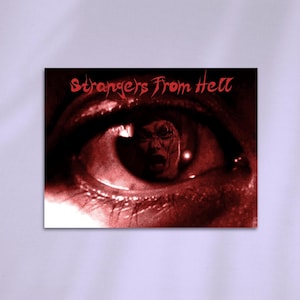 May include: A red-toned image featuring a close-up of an eye with the text "Strangers From Hell" in red. Inside the eye's pupil, a distorted, frightening face is visible, creating a horror theme.