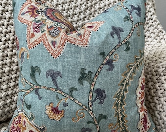 May include: A teal blue throw pillow with a floral pattern in shades of orange, red, green, and brown. The pillow has a paisley design and a textured fabric.
