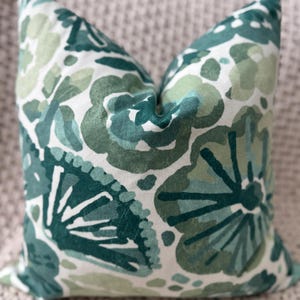 May include: A green and white throw pillow with a floral pattern. The pillow is made of a soft, comfortable fabric and features a variety of green shades.