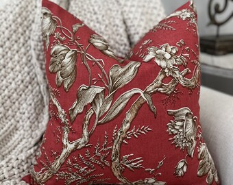 May include: Red pillow with a floral pattern in brown and white. The pillow is made of a linen fabric and has a square shape.