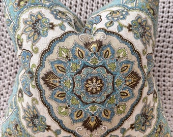 May include: A decorative throw pillow with a beige background and a large blue, brown, and green floral pattern.
