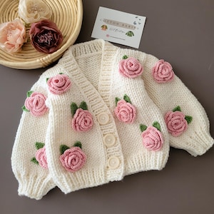 Handgemaakt gebreid babyvest met roze rozen