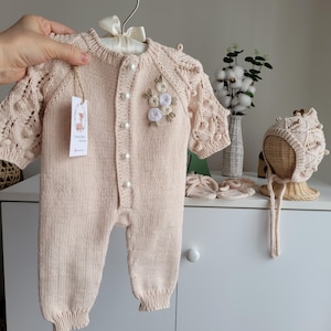 Ręcznie robiony na drutach kombinezon niemowlęcy z bawełny organicznej z kwiatowym haftem