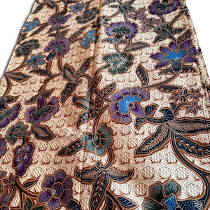 May include: A beige textile with a repeating floral pattern in shades of purple, blue, green, and brown. The flowers and leaves are stylized, with intricate details. The background has a subtle, textured design.