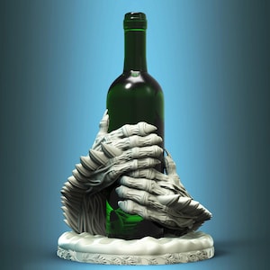 Può includere: Un portabottiglie in ceramica bianca a forma di due mani che tengono una bottiglia di vino in vetro verde.