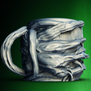Pu&ograve; includere: Una tazza in ceramica con un design unico che presenta un motivo testurizzato, organico e leggermente grottesco. La tazza ha un manico e sembra essere fatta di un materiale grigio chiaro.