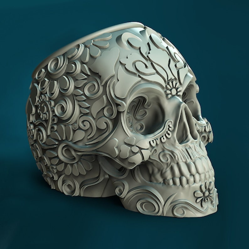 May include: A white ceramic skull planter featuring intricate floral designs. The skull is detailed with eye sockets, a nose, and a mouth.