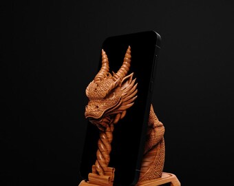 May include: A wooden phone stand with a dragon design. The dragon is carved in a light brown colour, with detailed scales and horns. A black phone is held upright by the dragon's head and body. The stand is made of wood.