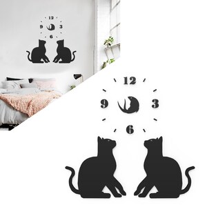 May include: Black wall clock featuring a cat silhouette design. The clock face has numbers at 12, 3, 6, and 9 o'clock, with a fish-shaped design in the center. Two black cat silhouettes are positioned below the clock.