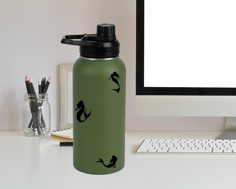 May include: A green stainless steel water bottle with a black lid and handle. The bottle has three black mermaid silhouettes on it.
