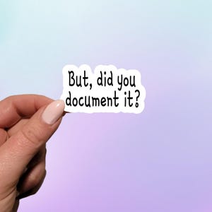 May include: White sticker with black text that reads "But, did you document it?"  A hand is holding the sticker.