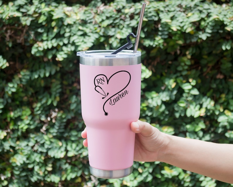 May include: Pink stainless steel tumbler with a black stethoscope design and the text "RN Lauren".