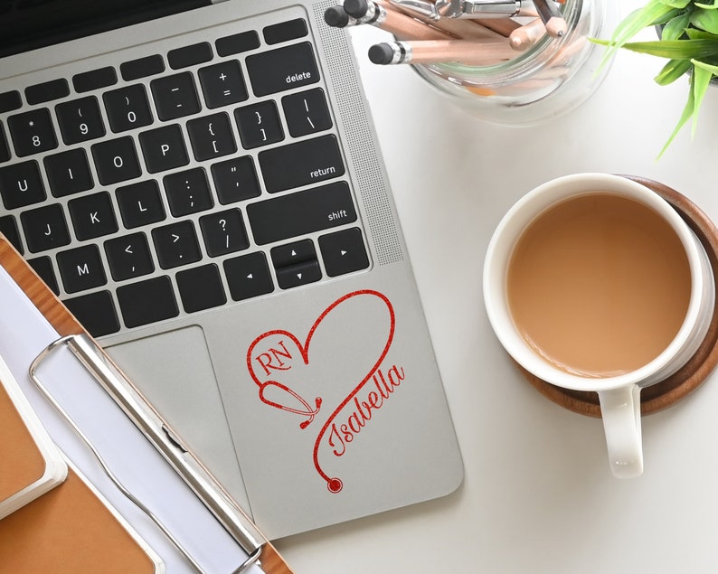 May include: A silver laptop with a red heart and stethoscope design that says "RN Isabella" on the top right corner of the laptop.