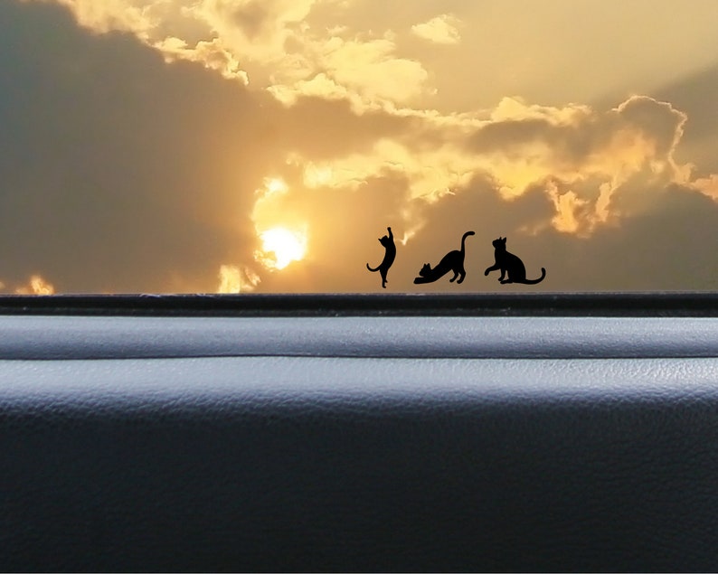 Puede incluir: Siluetas de cuatro gatos negros sobre un fondo de cielo de puesta de sol. Los gatos est&aacute;n en varias poses, incluyendo sentados, de pie y estir&aacute;ndose. El cielo es de un naranja y amarillo vibrante, con nubes blancas y esponjosas.