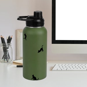 Puede incluir: Una botella de agua reutilizable verde con tapa y asa negras. La botella tiene tres siluetas de gatos negros en ella.