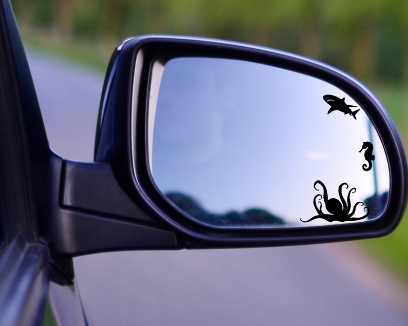 May include: A rearview mirror with a black octopus, a black shark, and a black seahorse silhouette sticker on the glass.