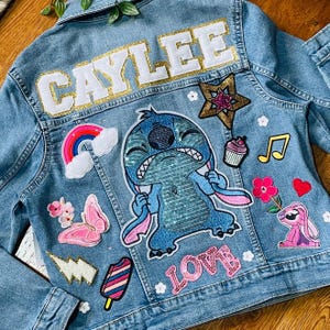May include: A blue denim jacket with various patches, including a rainbow, a cupcake, a musical note, a flower, a butterfly, a lightning bolt, an ice cream cone, a heart, a star, a Stitch character, and the word "LOVE". The jacket also has the name "CAYLEE" written on the back.