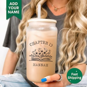 May include: A clear reusable tumbler with a black and white design of a book with flowers and the text "Chapter 13 Hannah".