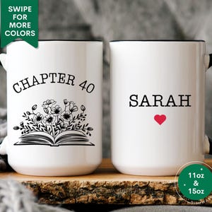 May include: Two white ceramic mugs with black handles and black rims. The mug on the left has the text "CHAPTER 40" and a black and white illustration of a book with flowers. The mug on the right has the text "SARAH" with a red heart. Both mugs are 11 oz and 15 oz.