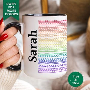 May include: White ceramic mug with a black handle and rim, featuring a rainbow pattern of stitched designs. The name "Sarah" is printed vertically in black. The mug has a capacity of 11oz or 15oz.