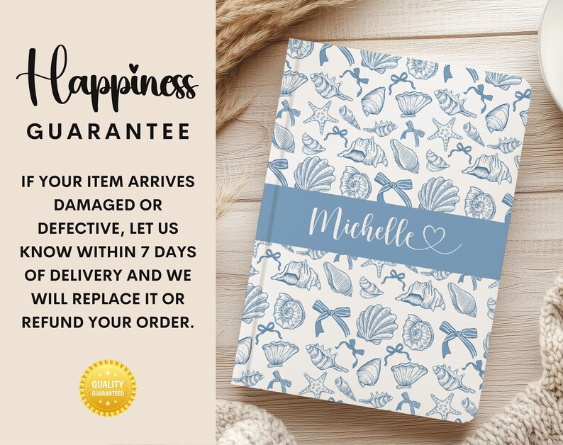 K&ouml;nnte beinhalten: Ein personalisiertes Notizbuch mit einem blau-wei&szlig;en Muschelmuster. Das Notizbuch hat ein blaues Band mit dem Namen "Michelle" in Schreibschrift. Der Text "Happiness Guarantee" ist ebenfalls sichtbar.