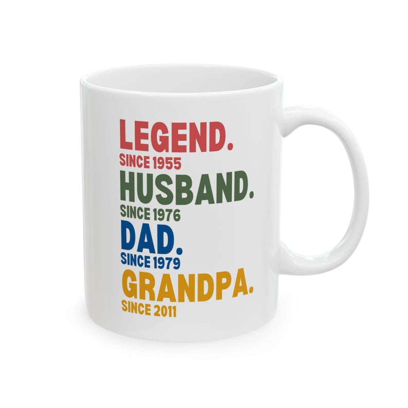 K&ouml;nnte beinhalten: Wei&szlig;e Keramik-Kaffeetasse mit dem Text "LEGEND. SINCE 1955 HUSBAND. SINCE 1976 DAD. SINCE 1979 GRANDPA. SINCE 2011" in bunten Farben.