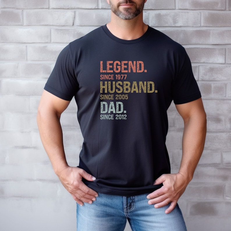 May include: A black t-shirt with a vintage-style graphic that reads "LEGEND. SINCE 1977. HUSBAND. SINCE 2005. DAD. SINCE 2012."