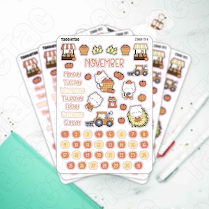 May include: A sheet of stickers featuring a fall harvest theme with cute cats. The stickers include a calendar for November, days of the week, a tractor, pumpkins, apples, corn, and a farm stand.