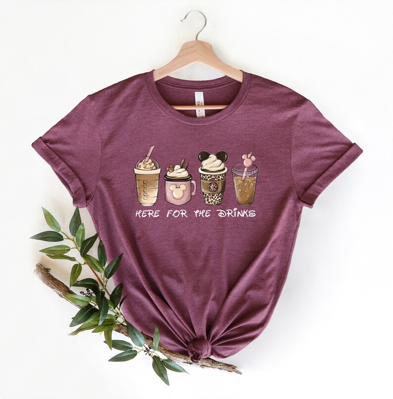 May include: A maroon t-shirt with a graphic of four different coffee drinks. The text "Here for the drinks" is printed below the drinks.