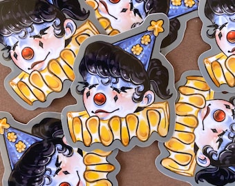 May include: A collection of stickers featuring a stylized clown face with black hair, a red nose, and a blue party hat adorned with yellow flowers. The clown has a yellow ruffled collar and a pale complexion. The stickers have a gray border.