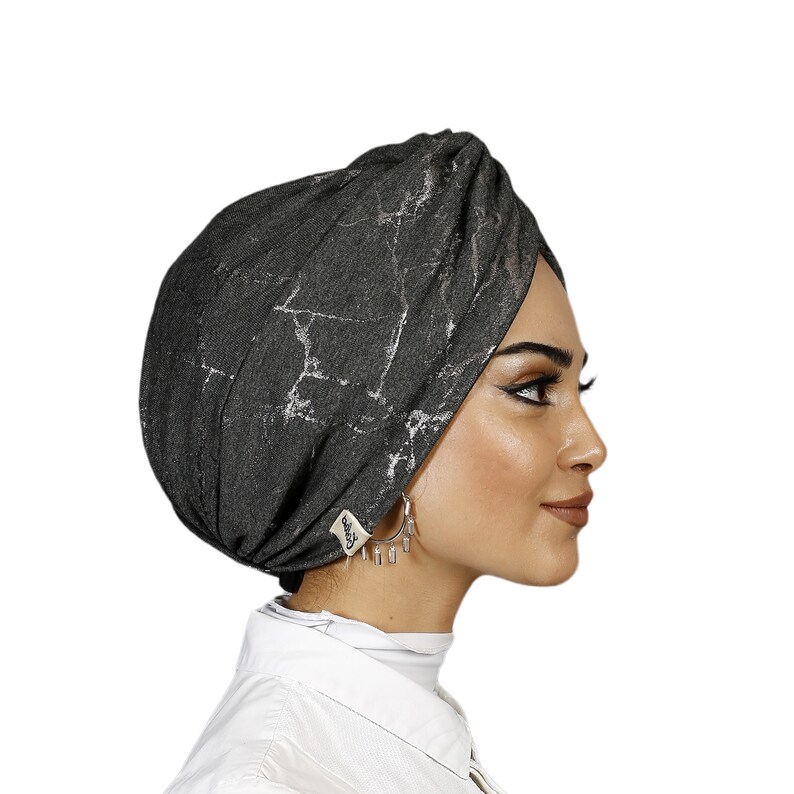 May include: A gray turban with a silver marble pattern. The turban is made of a soft, stretchy fabric and is designed to be comfortable and easy to wear.