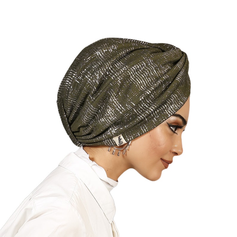 May include: A green turban with a silver metallic pattern. The turban is made of a soft, stretchy fabric and is designed to be worn comfortably.