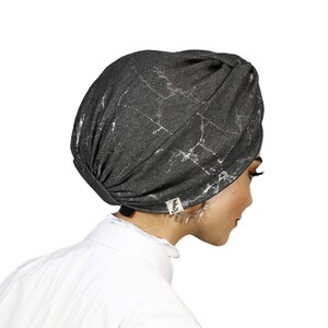 May include: A gray turban with a silver marble pattern. The turban has a small black label with the word "baby" on it.