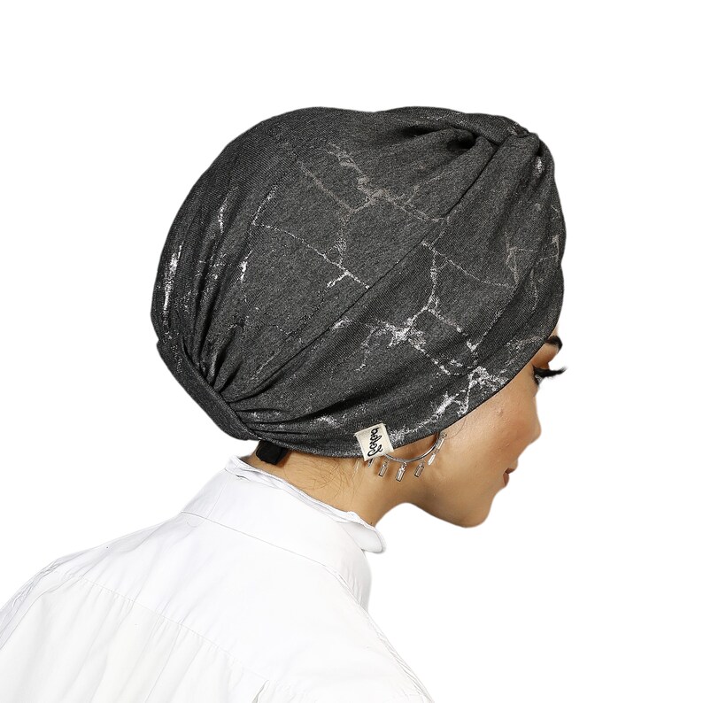 May include: A gray turban with a silver marble pattern. The turban has a small black label with the word "baby" on it.