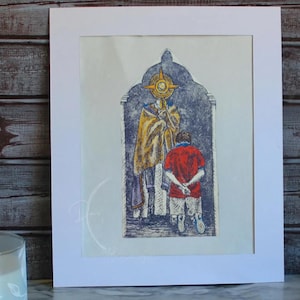 May include: An artistic print featuring a religious scene with a figure in a yellow robe and a person in a red shirt. The print is framed in a white mat, set against a rustic wooden background. The artwork uses blue, yellow, and red tones.