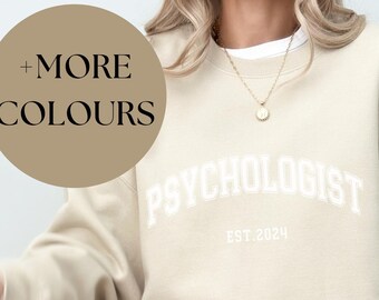 May include: A beige sweatshirt with the text "PSYCHOLOGIST EST. 2024" in white.