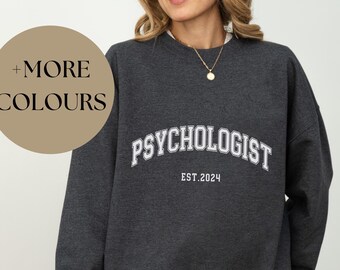 May include: Dark gray sweatshirt with the text "PSYCHOLOGIST EST. 2024" in white.