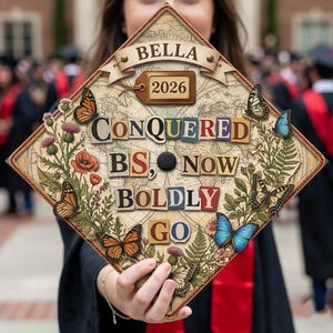 Puede incluir: Un birrete de graduación decorado con mariposas y elementos florales. El birrete presenta el nombre "BELLA" y el año "2026". Las palabras "CONQUERED BS, NOW BOLDLY GO" se muestran en un estilo collage.