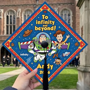 Puede incluir: Un gorro de graduación azul decorado con la temática de Toy Story. Presenta a Buzz Lightyear, Woody y otros personajes. El texto dice "To infinity and beyond!" y "Ardy 2016".