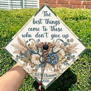 May include: A white ceramic mug with a black handle and the text "But First, Coffee" in a bold, black font. The mug is set against a blurred background, highlighting its clean design.