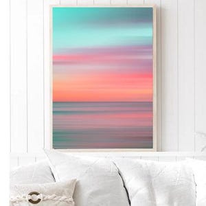 May include: Abstract art print featuring a blurred, colorful sunset over a calm ocean. The colors are a mix of pink, orange, blue, and purple, creating a dreamy and serene atmosphere.