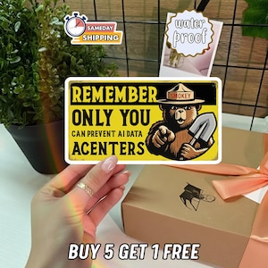 May include: A rectangular sticker with a yellow background featuring a brown bear wearing a hat labeled SMOKEY, holding a shovel, and pointing forward. The text reads REMEMBER ONLY YOU CAN PREVENT AI DATA ACENTERS in bold black capital letters.