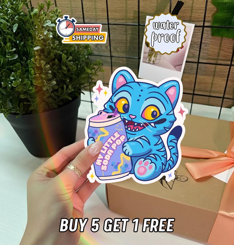 K&ouml;nnte beinhalten: Blauer Cartoon-Katzen-Aufkleber, der eine Soda-Dose mit der Aufschrift "MY LITTLE SODA POP" h&auml;lt. Der Aufkleber ist wasserfest und tr&auml;gt den Text "BUY 5 GET 1 FREE".