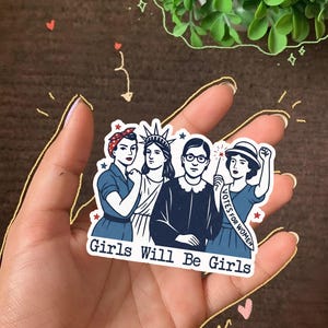 Pode incluir: Um autocolante com uma ilustra&ccedil;&atilde;o de quatro mulheres em azul, branco e vermelho. Uma mulher usa uma bandana, outra uma coroa e uma terceira usa &oacute;culos. O texto "Girls Will Be Girls" est&aacute; na parte inferior, e uma mulher tem uma faixa que diz "VOTES FOR WOMEN."