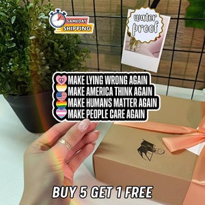 May include: A sticker with the text "MAKE LYING WRONG AGAIN", "MAKE AMERICA THINK AGAIN", "MAKE HUMANS MATTER AGAIN", and "MAKE PEOPLE CARE AGAIN". The sticker has a heart, peace sign, American flag, rainbow, and transgender flag. The image also includes a box with a bow and the text "BUY 5 GET 1 FREE".