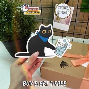 May include: A black cat sticker with yellow eyes and a blue bandana, holding a sticker of a glass of ice water. The image also includes a "water proof" sticker and text that reads "BUY 5 GET 1 FREE".