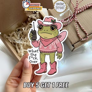 May include: A sticker featuring a cartoon frog wearing a pink cowboy hat, sweater, and boots, holding a walkie-talkie. The text "What the F*ck, Over" is below the frog. The sticker is labeled "water proof".